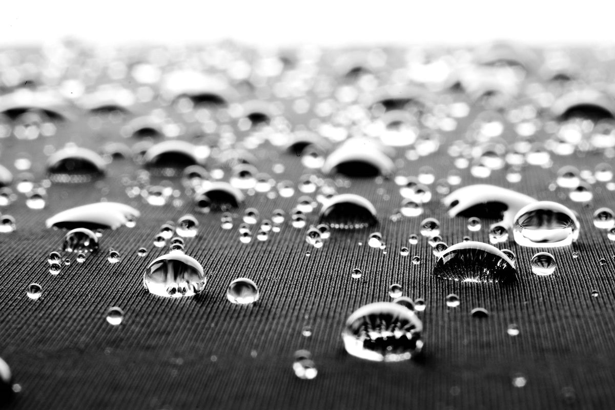 Water beading on the surface of a black wetsuit jersey fabric instead of soaking in