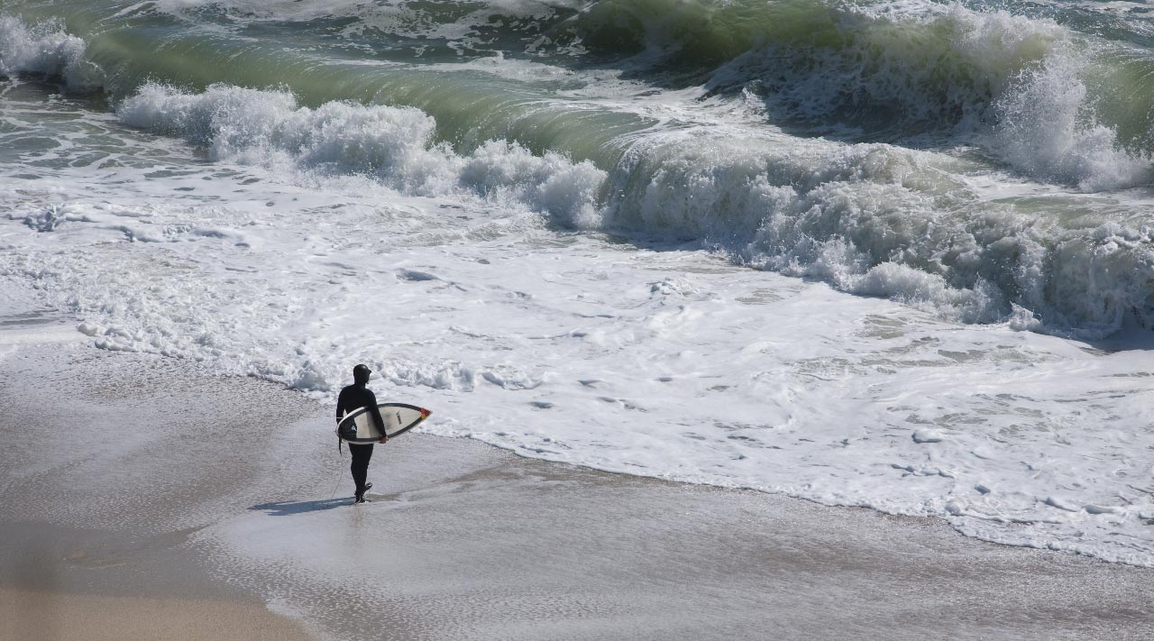 Surfer in an Isurus Hooded Wetsuit about to paddle out in big conditions